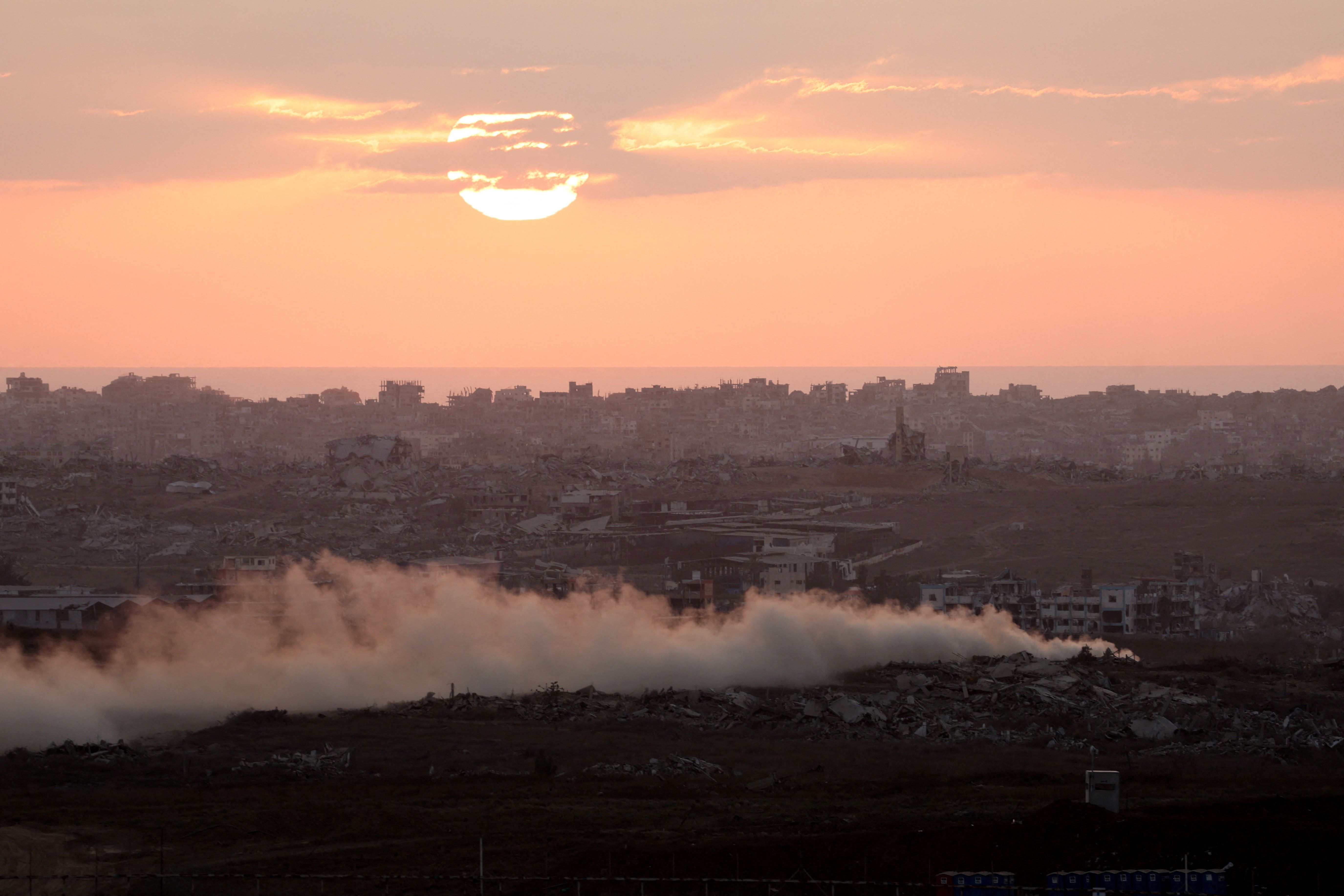 Fumaça sobe de Gaza enquanto o sol se põe, visto do lado israelense da fronteira entre Israel e Gaza