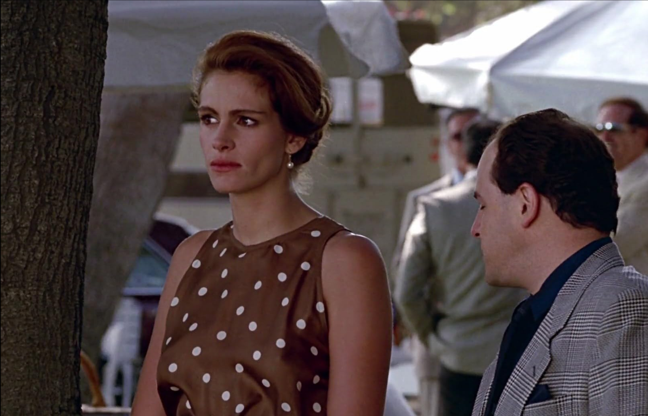 Julia Roberts usando um vestido marrom e branco com bolinhas no filme de 1990, "Uma Linda Mulher" • Reprodução