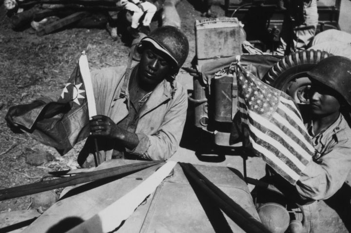 Um oficial americano fixa uma bandeira da China enquanto um oficial chinês fixa uma bandeira americana durante a Segunda Guerra Mundial, em 6 de fevereiro de 1945 • Archive Photos/Getty Images
