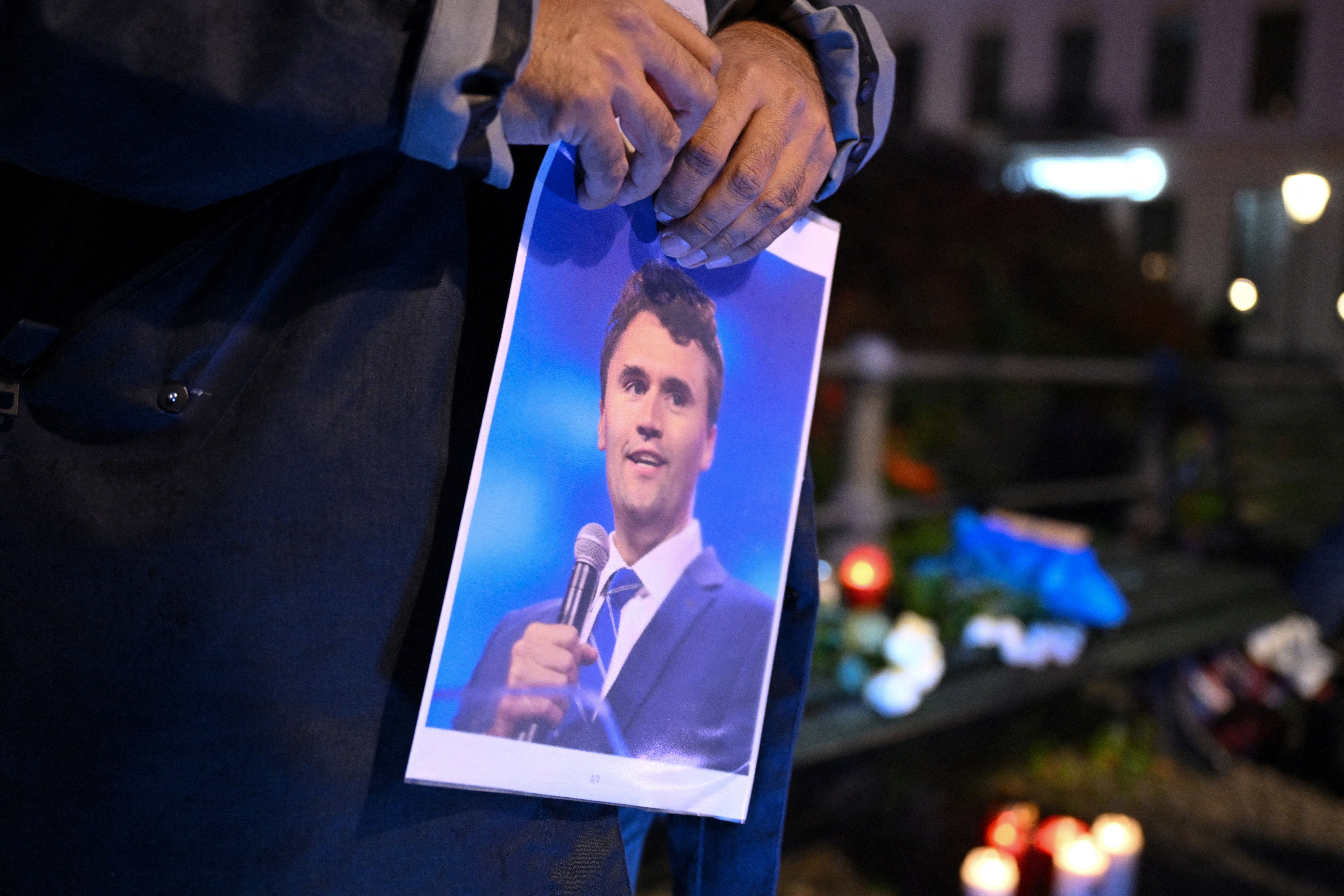 Homem segura foto de Charlie Kirk durante vigília em frente à Embaixada dos Estados Unidos em Berlim, Alemanha