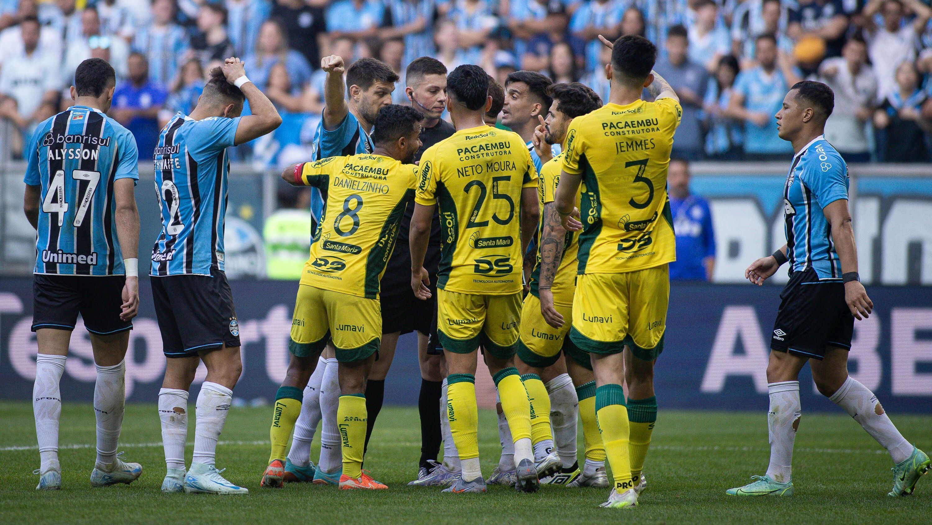 Jogadores de Grêmio e Mirassol cercam a arbitragem, em jogo válido pela 23ª rodada do Brasileirão