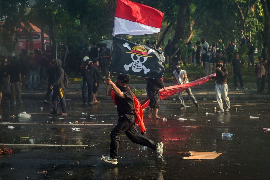 Manifestante carrega a bandeira nacional da Indonésia e uma bandeira pirata do anime japonês One Piece durante um protesto em frente à residência do governador em Surabaya, em 29 de agosto