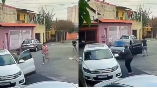 Após anunciarem o roubo, um carro preto se aproxima da cena e o policial desce do veículo