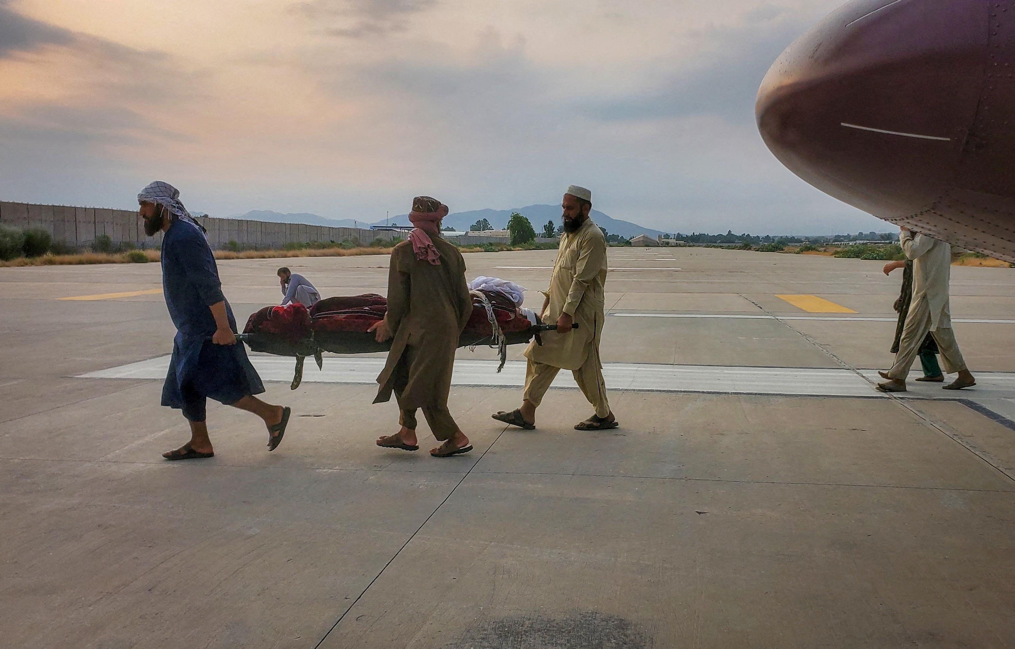 Pessoas carregam uma vítima de terremoto em um aeroporto em Jalalabad