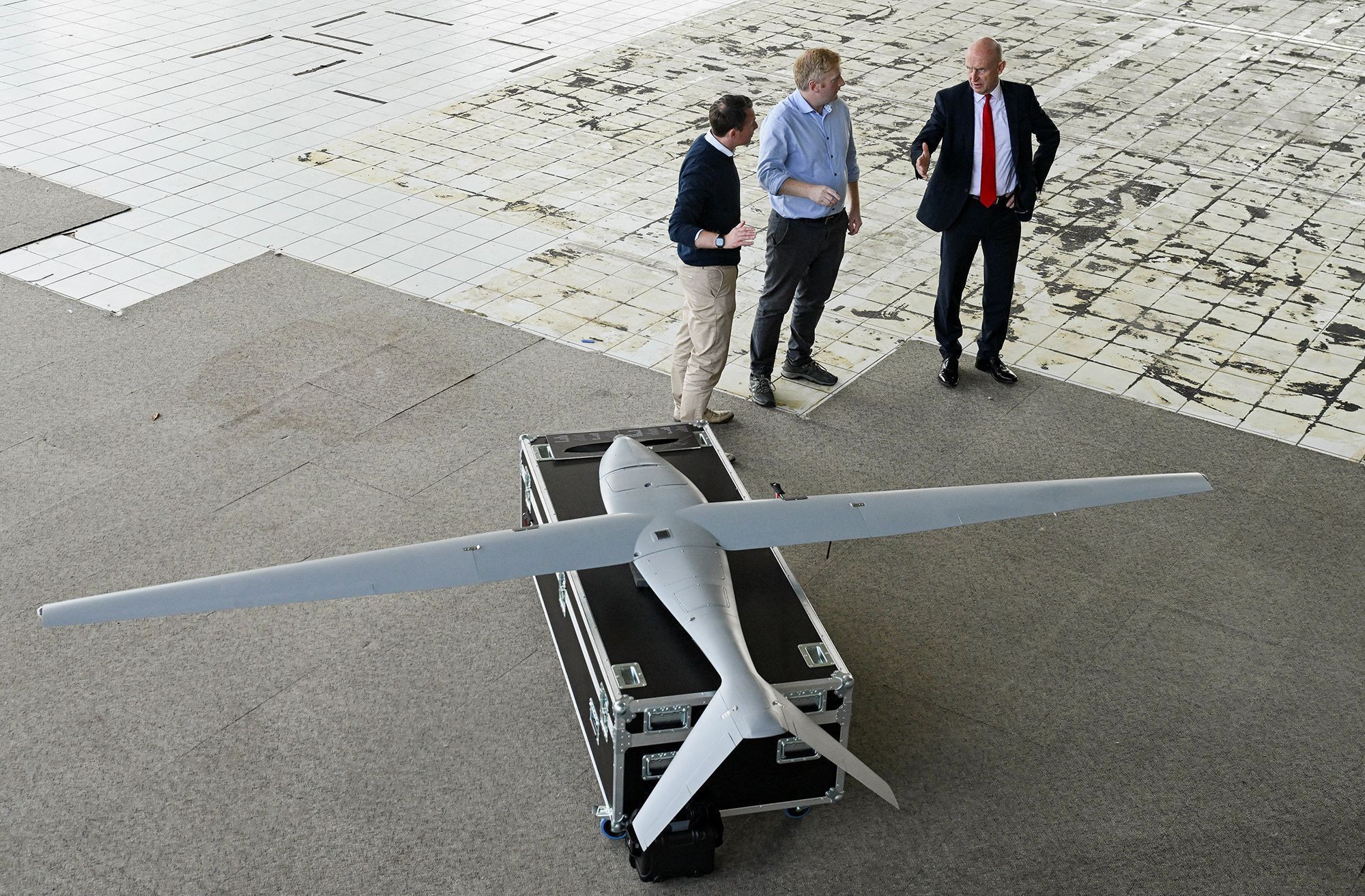 O secretário de Defesa britânico, John Healey (à direita), juntamente com o diretor de Defesa da Tekever, Karl Brew, e o vice-diretor de Defesa da Tekever, Scott McClelland (à esquerda), observam um drone durante um tour por uma nova unidade de produção de drones militares da Tekever, em Swindon, sul da Inglaterra • Jaimi Joy/AFP/Getty Images via CNN Newsource