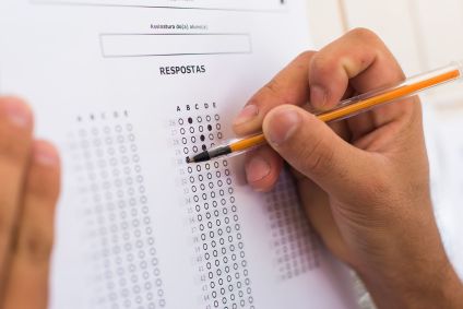 Mão assinalando questões de uma prova