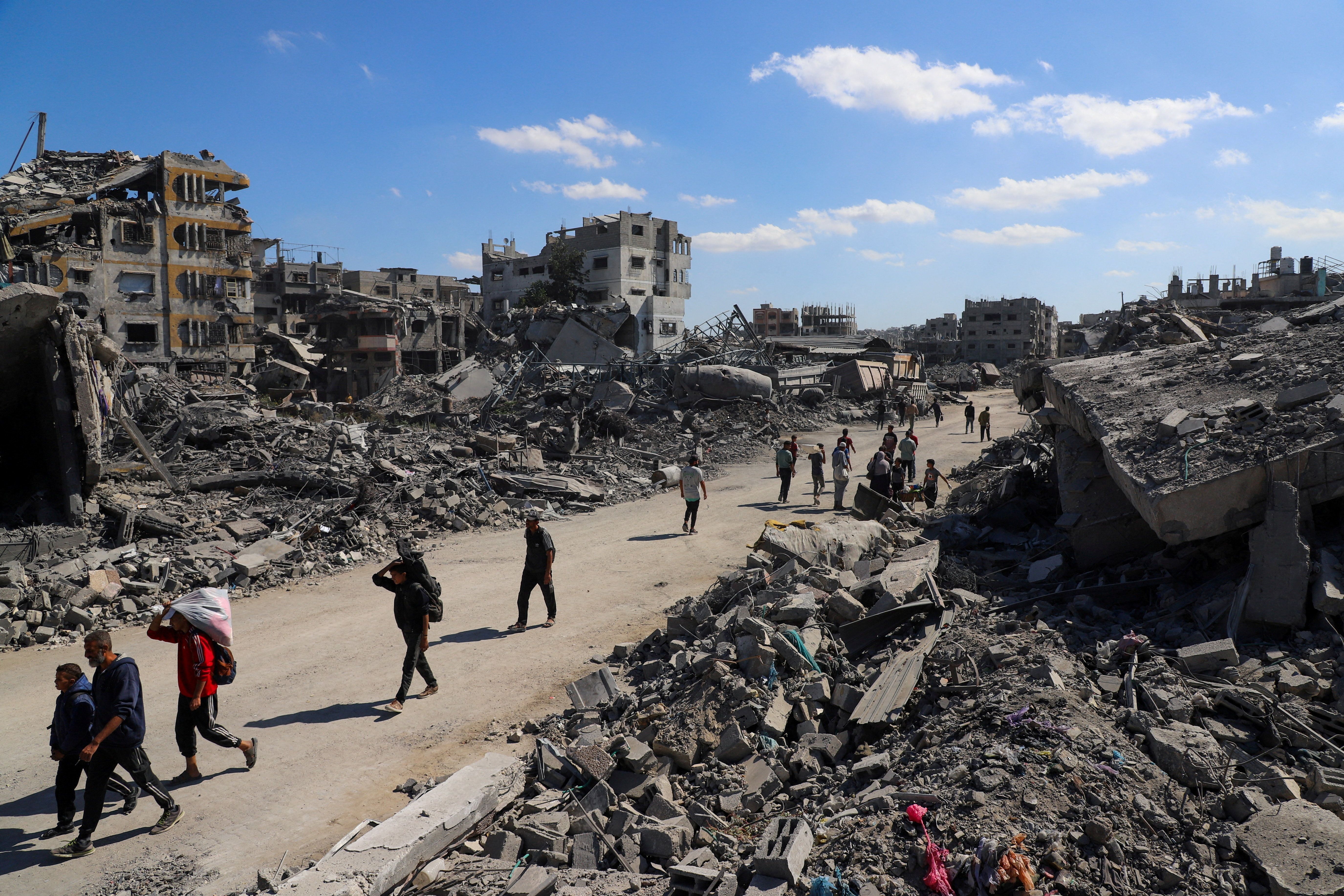 Palestinos caminham em meio a destroços na Cidade de Gaza