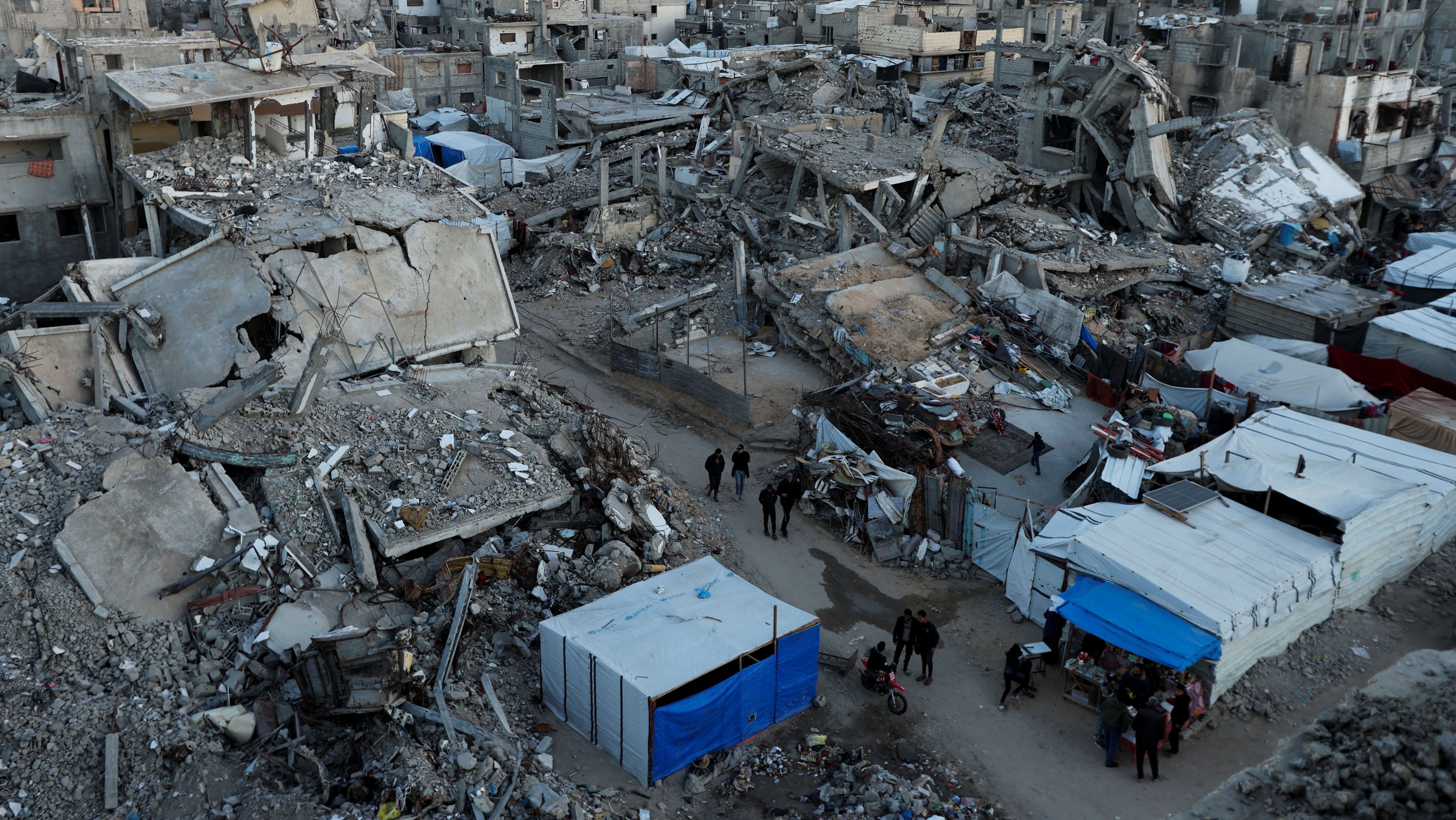 Palestinos caminham em meio a destroços em Khan Younis, na Faixa de Gaza