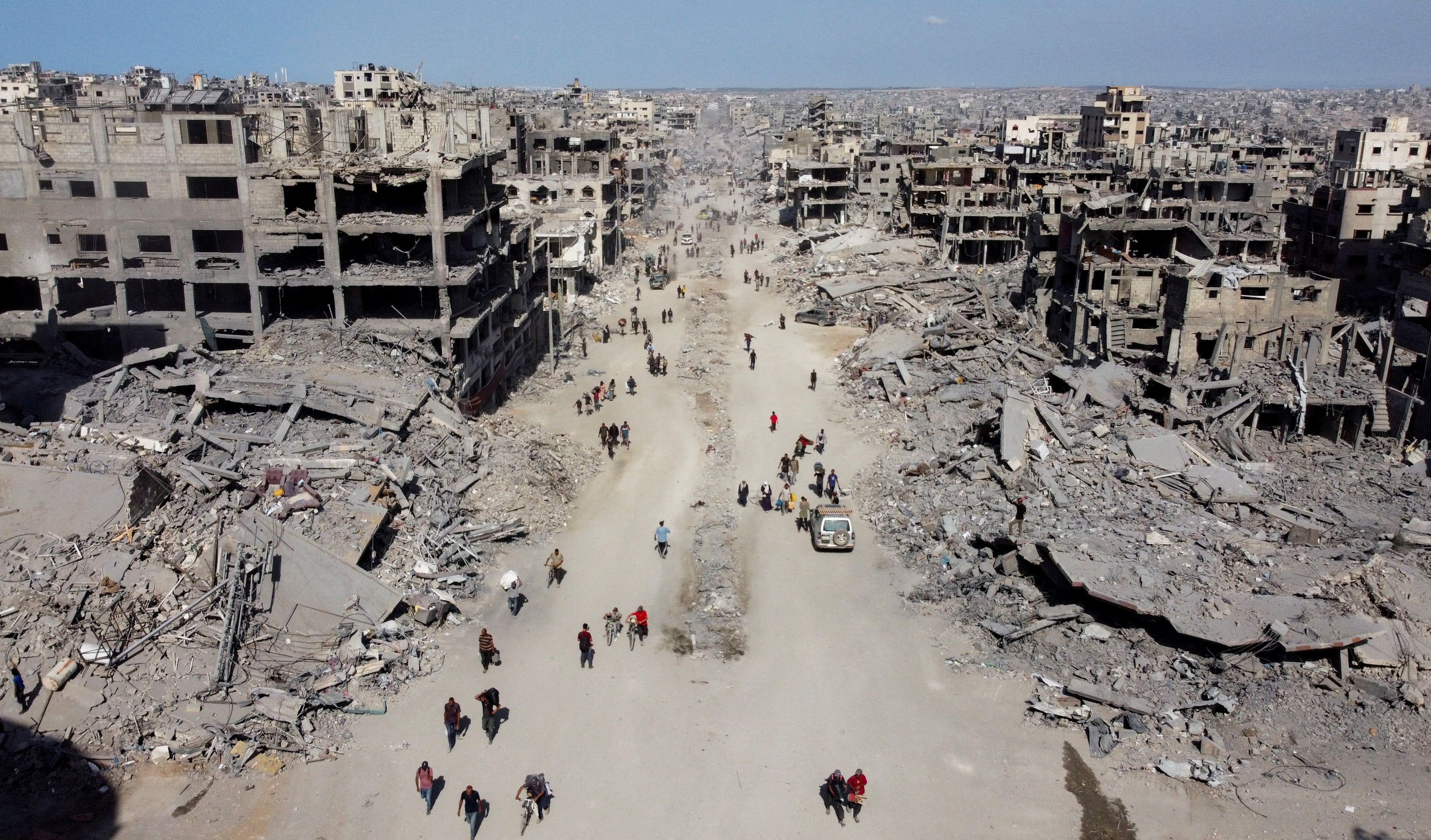 Palestinos caminhando em meio aos escombros em Gaza após retirada de tropas israelenses