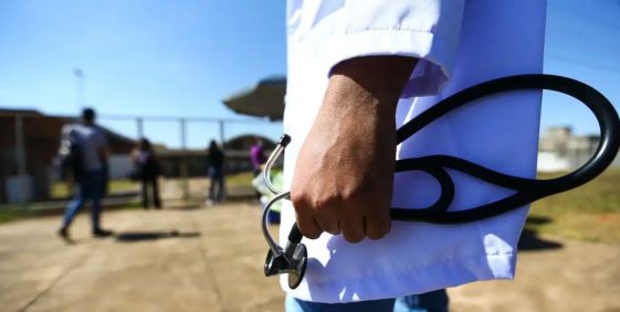 Homem de jaleco segura um estetoscópio