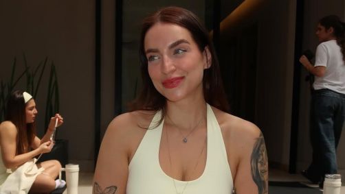 mulher, branca, de olhos azuis, cabelos lisos e castanhos, usando uma roupa de academia amarela, sorrindo