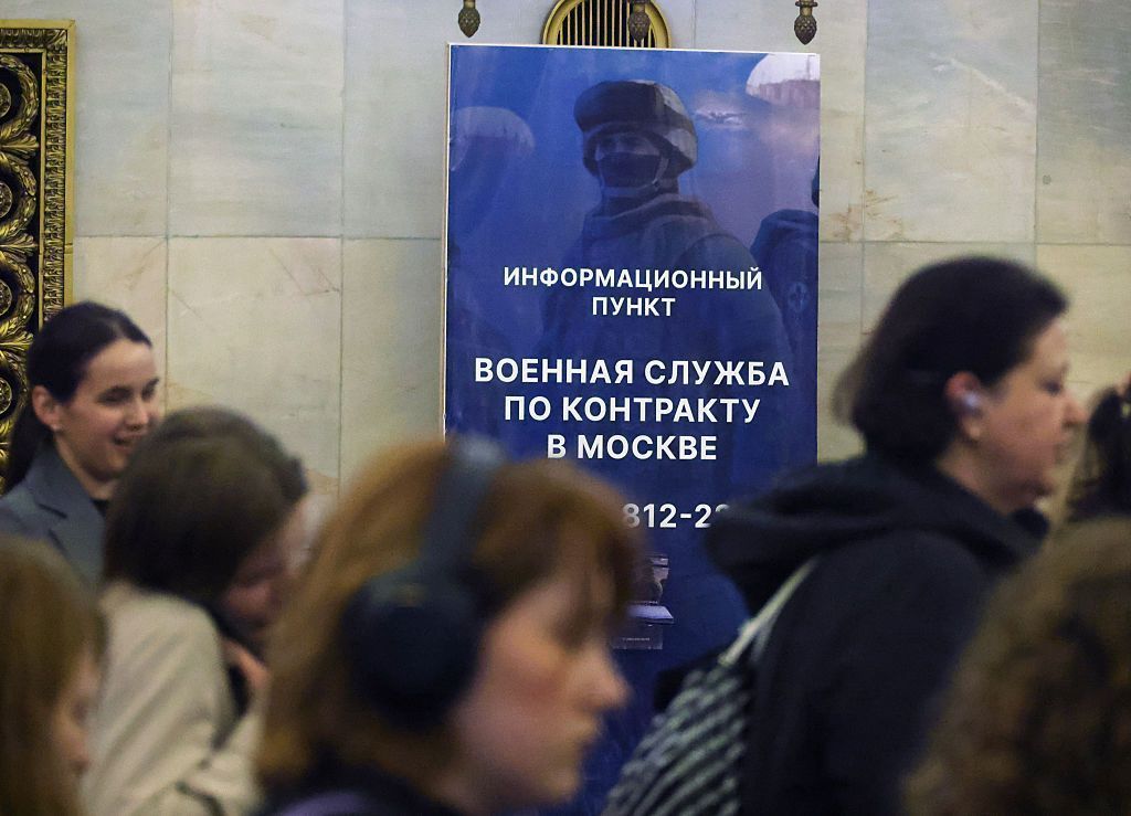 Passageiros passam por uma placa de recrutamento para o serviço nas Forças Armadas Russas, instalada na Estação Smolenskaya do Metrô de Moscou, em 19 de agosto de 2025