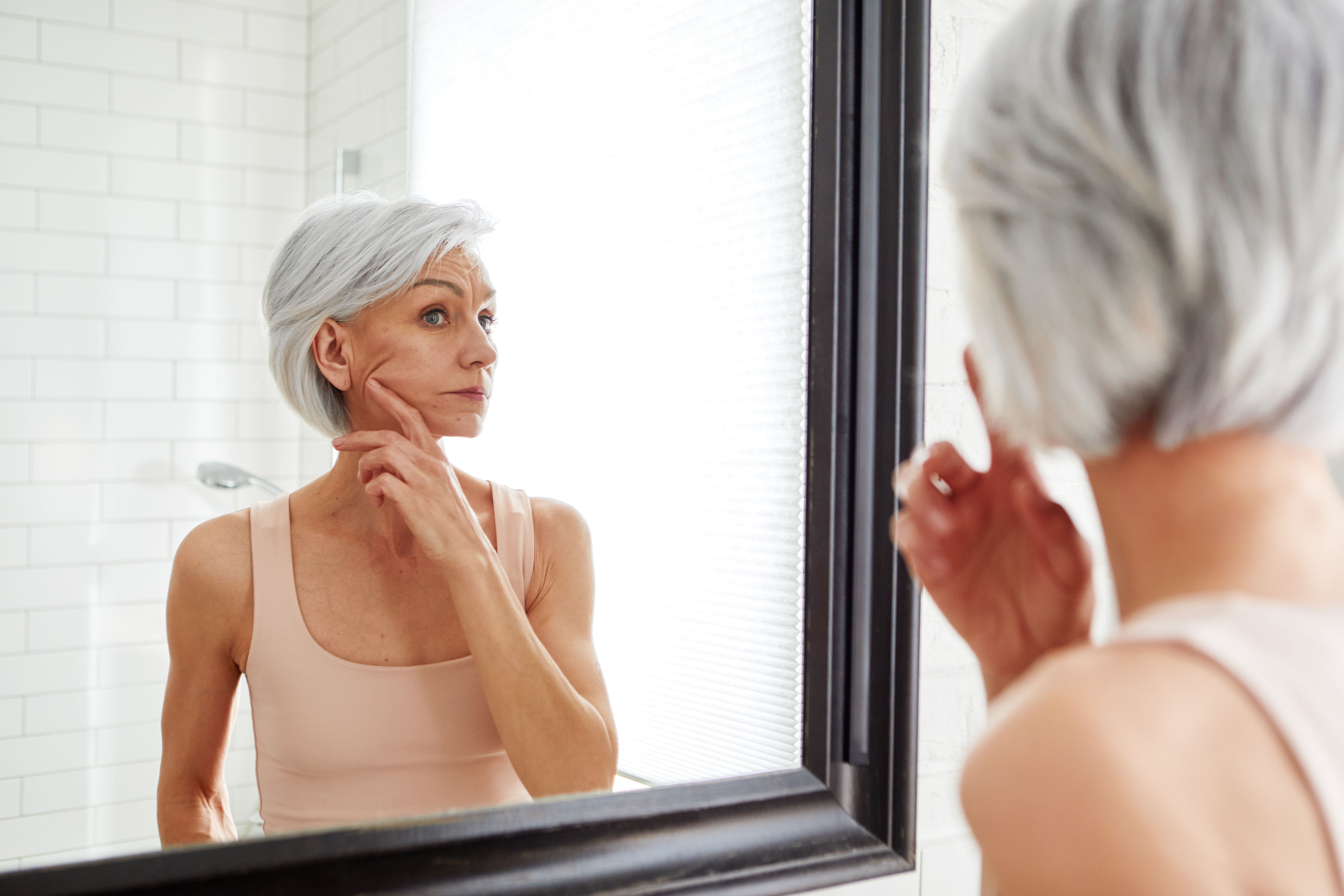 Elderly woman at mirror in bathroom
