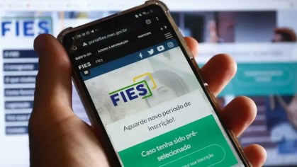 mão segura celular aberto na páfina do Fies