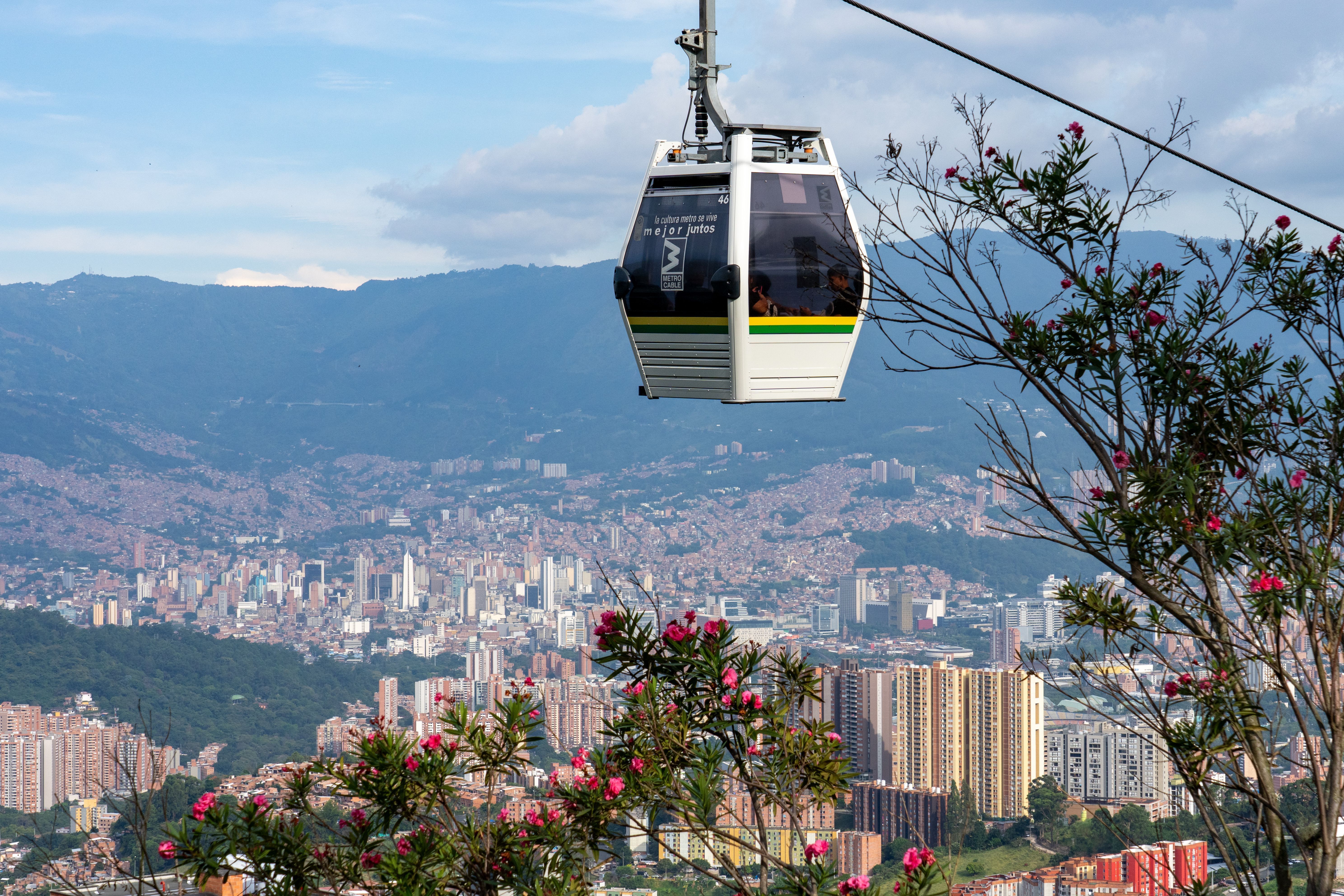 Uma gôndola do sistema Metrocable de Medellín com o centro de Medellín, Colômbia, ao fundo. • Jon G. Fuller/VW Pics/Universal Images Group via Getty Images