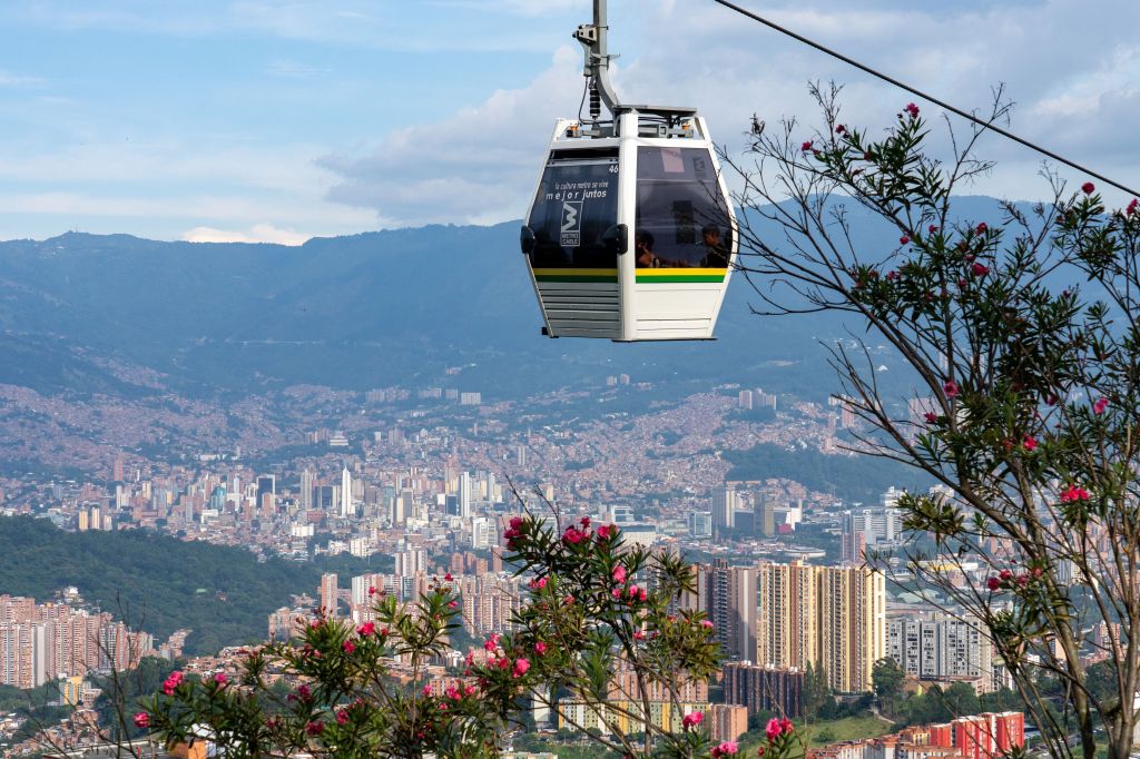 Uma gôndola do sistema Metrocable de Medellín com o centro de Medellín, Colômbia, ao fundo.