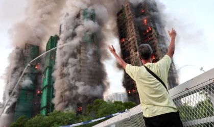 Homem observa incêndio em complexo residencial em Hong Kong