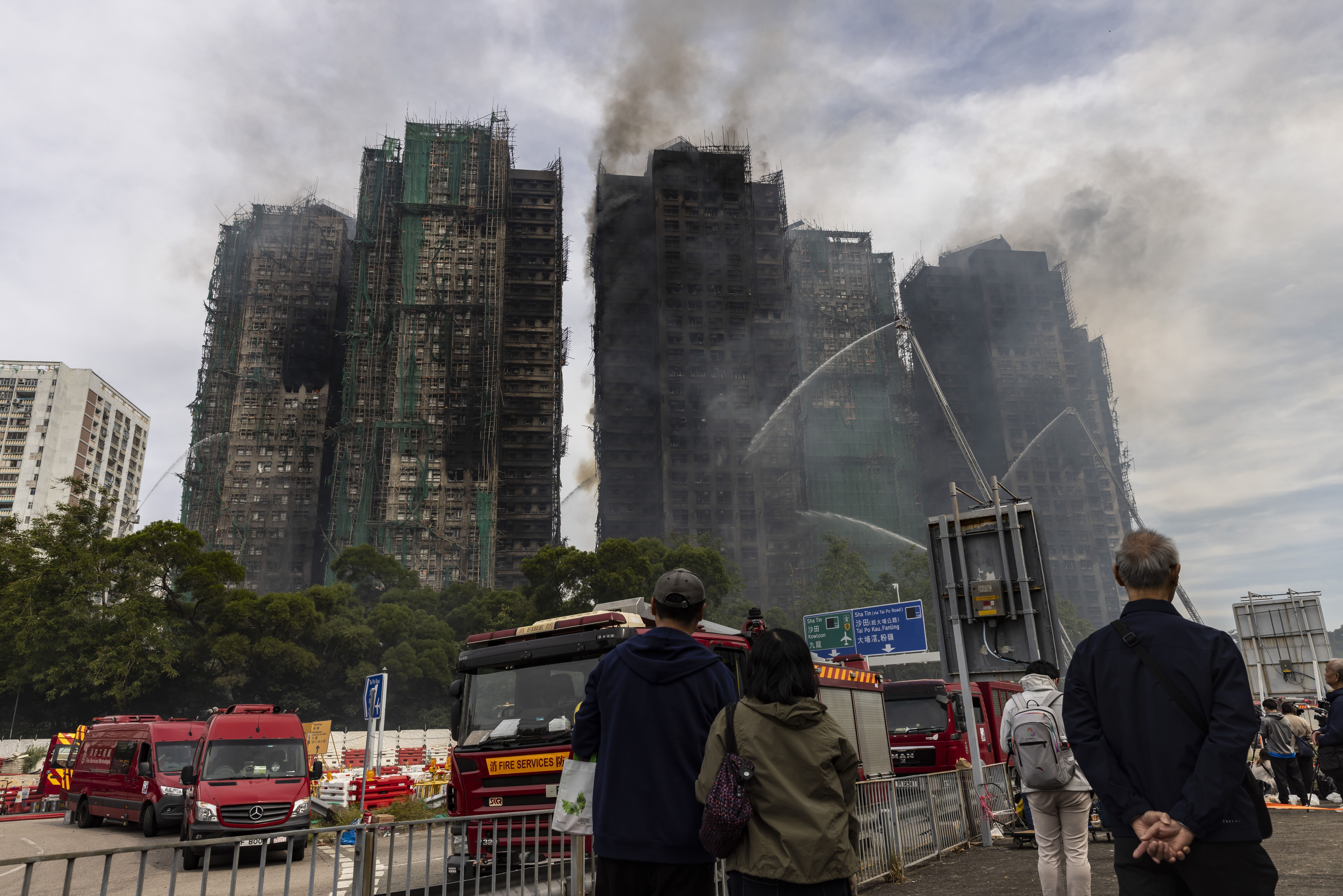Pessoas observam prédios residenciais atingidos por incêndio em Hong Kong