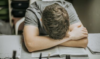 Estudante debruçado sobre a carteira