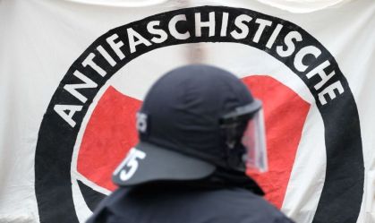 Policial em frente a uma faixa da Antifa durante uma manifestação de esquerda na Alemanha