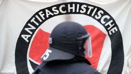 Policial em frente a uma faixa da Antifa durante uma manifestação de esquerda na Alemanha