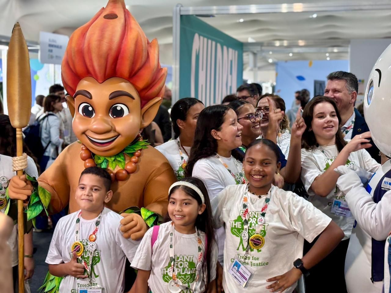 Crianças posam ao lado do mascote da COP30, o Curupira • Divulgação