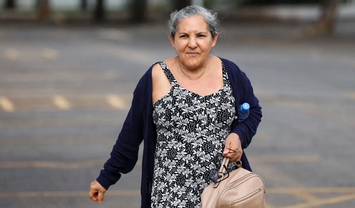 Mulher idosa carrega mochila enquanto caminha pela rua
