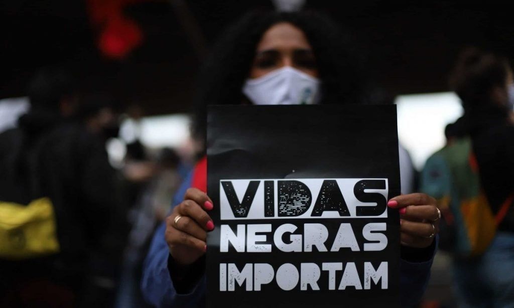 Mulher segura cartaz em protesto contra racismo onde está escrito "vidas negras importam'