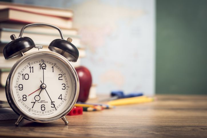 Alarm clock with back to school supplies in background.