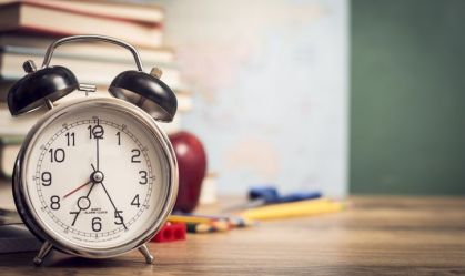 Alarm clock with back to school supplies in background.