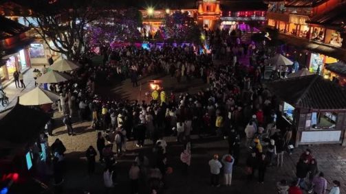 Moradores e turistas dão as mãos na Cidade Antiga de Lijiang, na província de Yunnan, para celebrar o Ano Novo