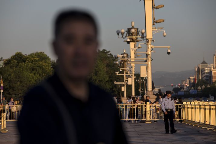 Um policial passa por câmeras de vigilância instaladas em postes na Praça Tiananmen, em Pequim, em 31 de maio de 2019 • Giulia Marchi/Bloomberg/Getty Images via CNN Newsource
