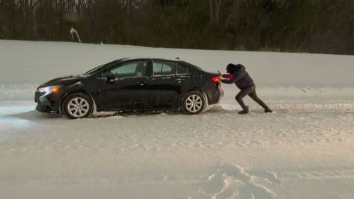 Homem empurra veículo na neve nos Estados Unidos