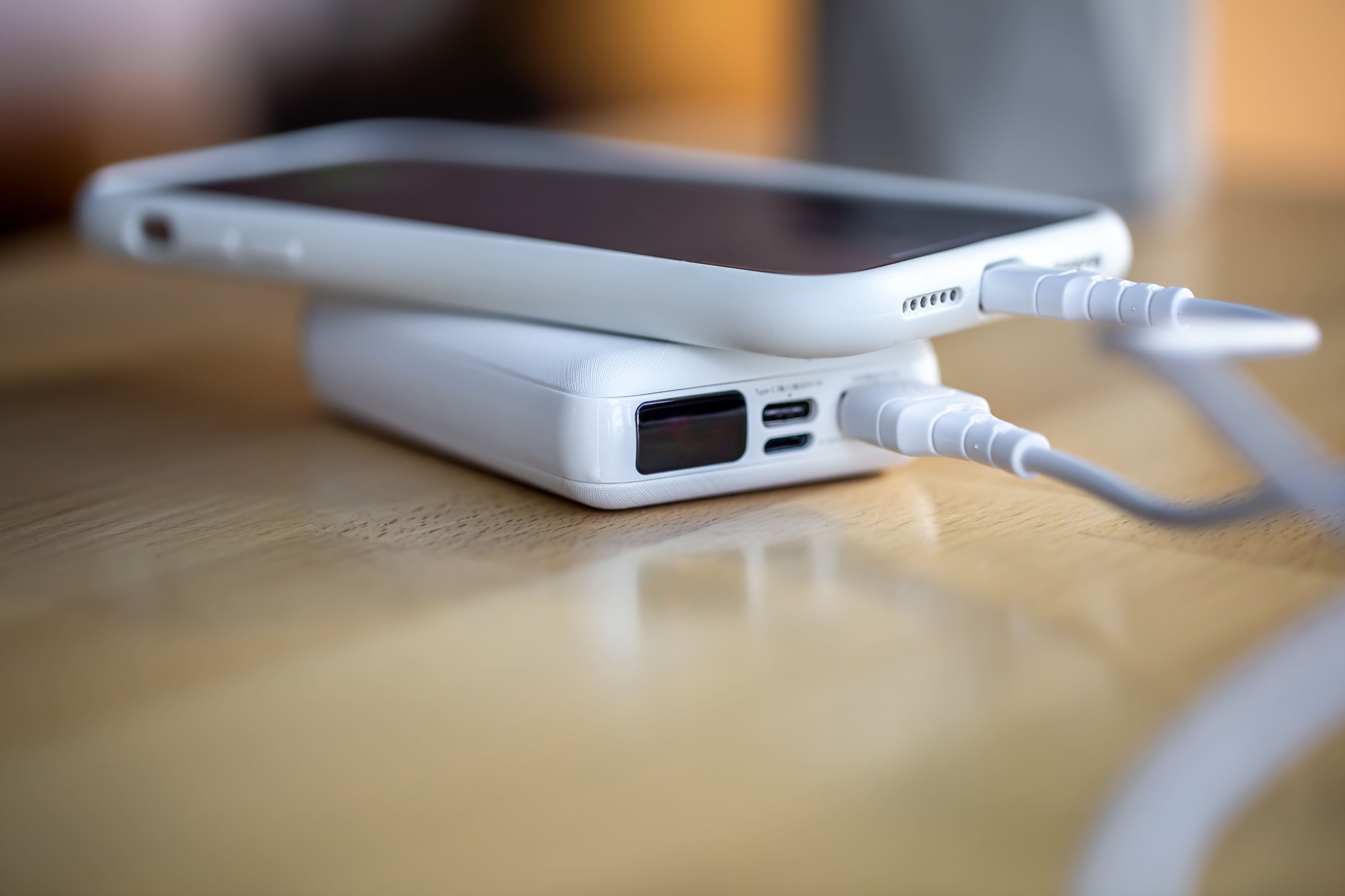 A smartphone is charged from a small white power bank.