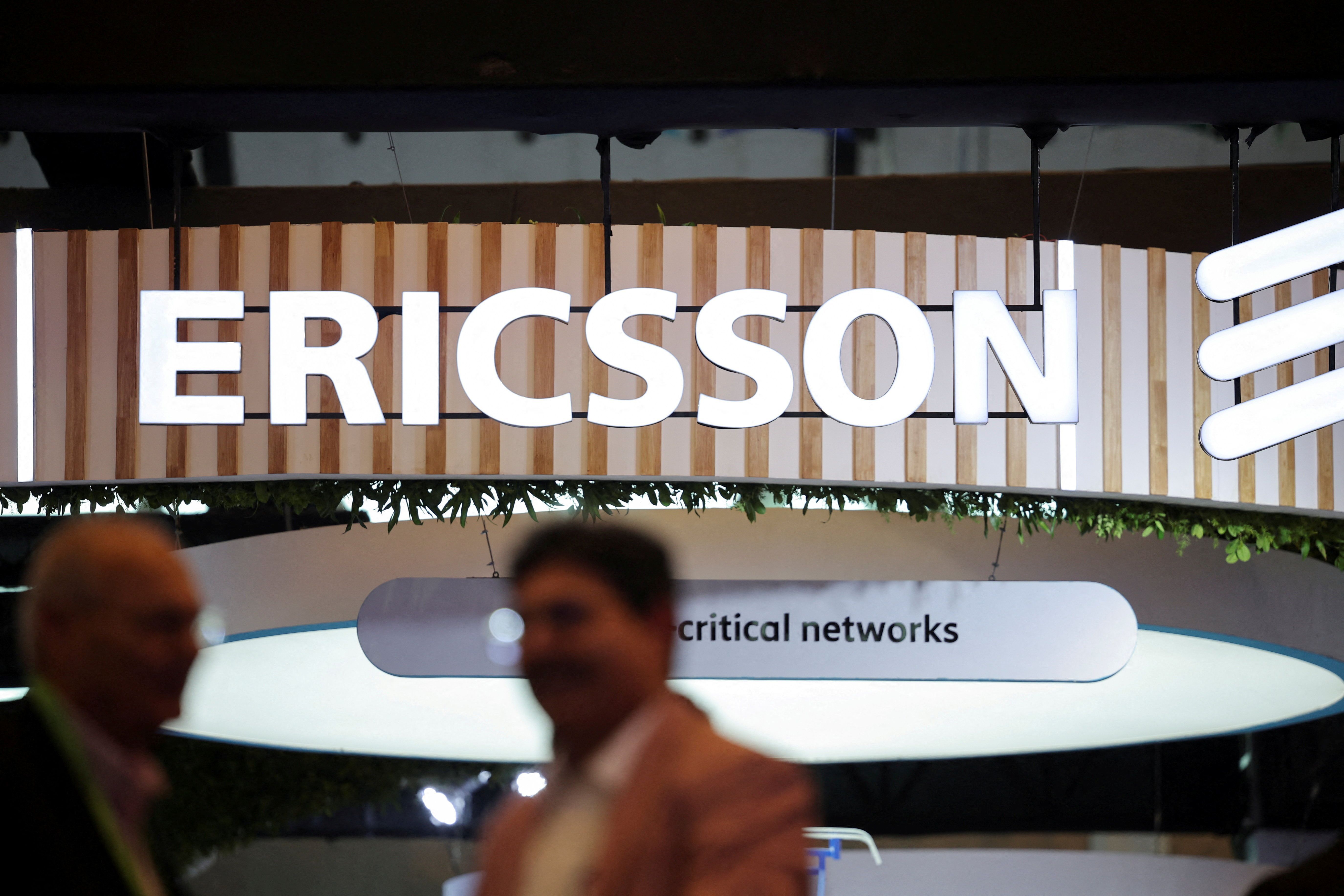 Participantes conversando perto do estande da Ericsson na India Mobile Congress 2025, em Nova Délhi, Índia