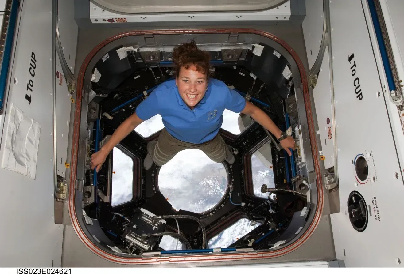 Dottie Metcalf-Lindenburger posa para uma foto na cúpula da Estação Espacial Internacional em 17 de abril de 2010, enquanto o ônibus espacial Discovery permanece acoplado à estação • Nasa