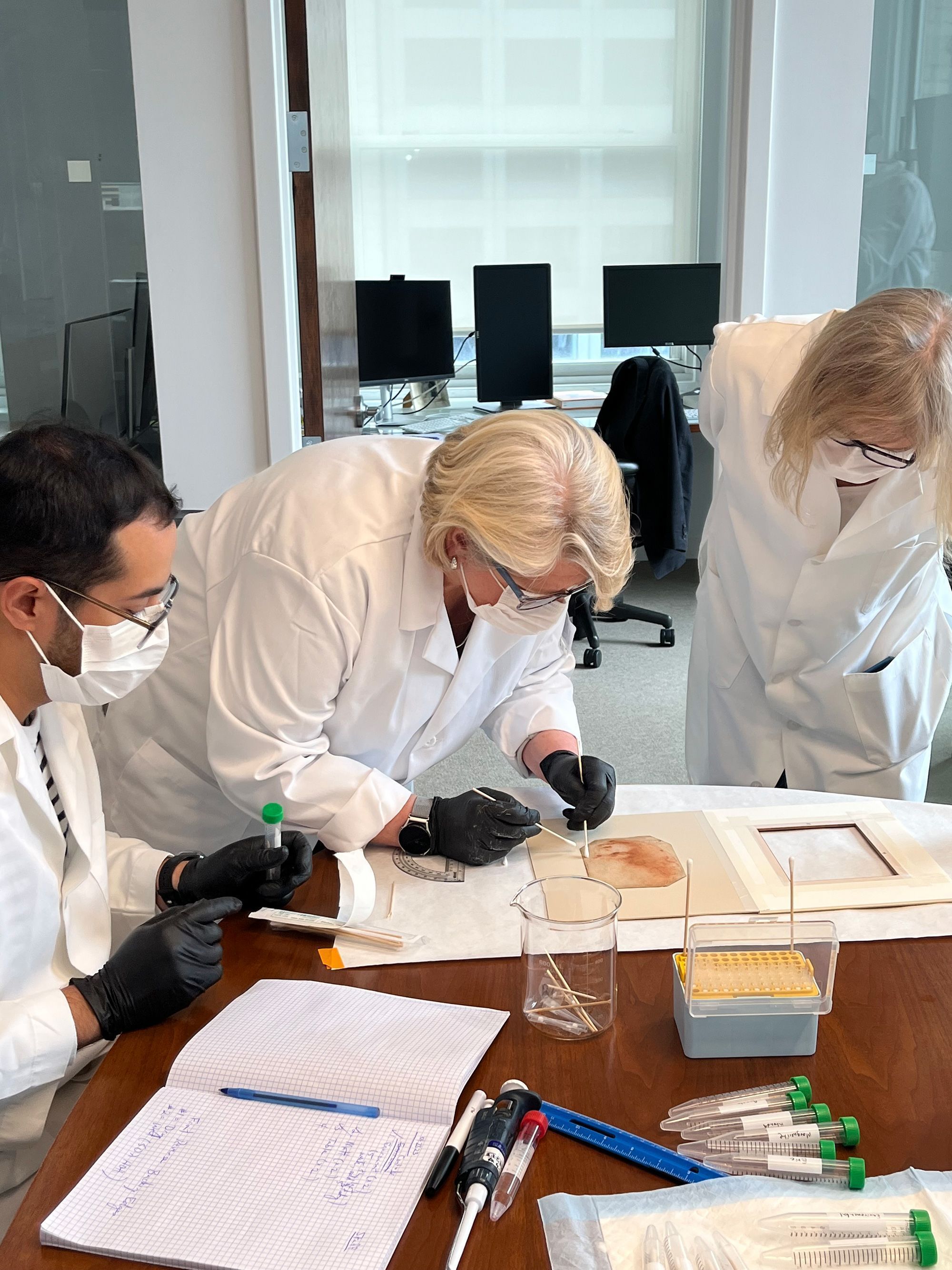 O geneticista microbiano Norberto Gonzalez-Juarbe (à esquerda) e a bióloga forense Rhonda Roby (ao centro) coletam amostras do desenho "Criança Sagrada" enquanto a colecionadora Angela Zimm observa • Marguerite Mangin via CNN Newsource