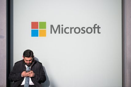 Homem usando telefone ao lado de um logotipo da Microsoft durante a 56ª reunião anual do Fórum Econômico Mundial, em Davos, Suíça