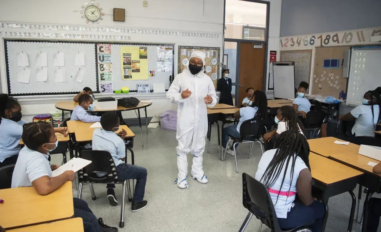 Kenneth Harris II aparece vestindo um traje de proteção, usado durante a montagem de espaçonaves para evitar contaminação, enquanto conversa com alunos em 18 de novembro de 2021, na Escola Primária Garfield, em Washington, DC • Joel Kowsky/Nasa