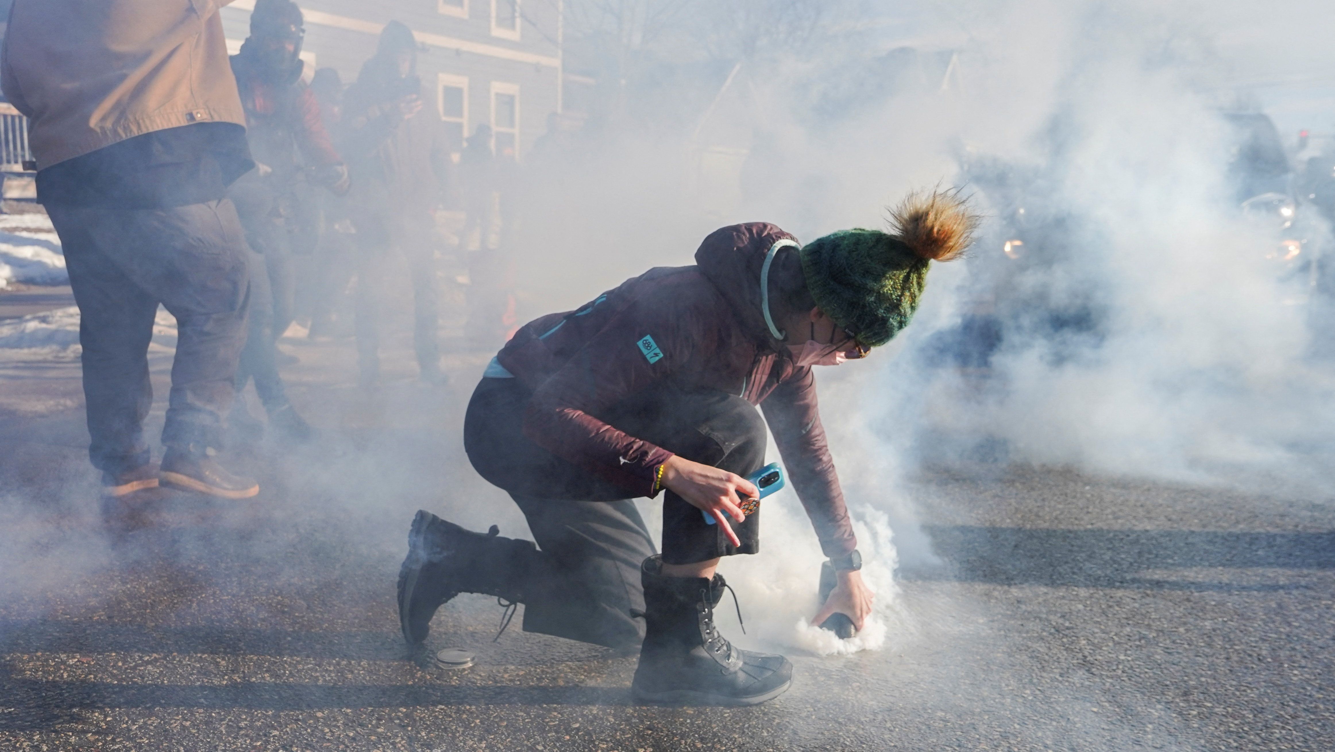 Manifestantes cobre lata de gás lacrimogêneo durante protesto contra agentes de imigração em Minneapolis, nos Estados Unidos