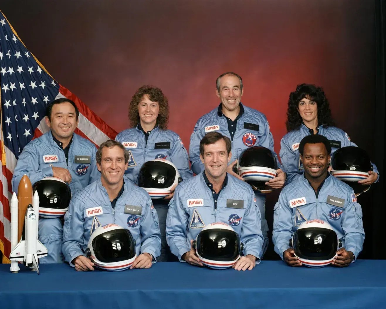 Membros da tripulação do Challenger (da esquerda para a direita, na primeira fila): Michael J. Smith, Francis R. (Dick) Scobee e Ronald E. McNair; (na segunda fila, da esquerda para a direita): Ellison S. Onizuka, Sharon Christa McAuliffe, Gregory Jarvis e Judith A. Resnik posam juntos em dezembro de 1985 • Nasa