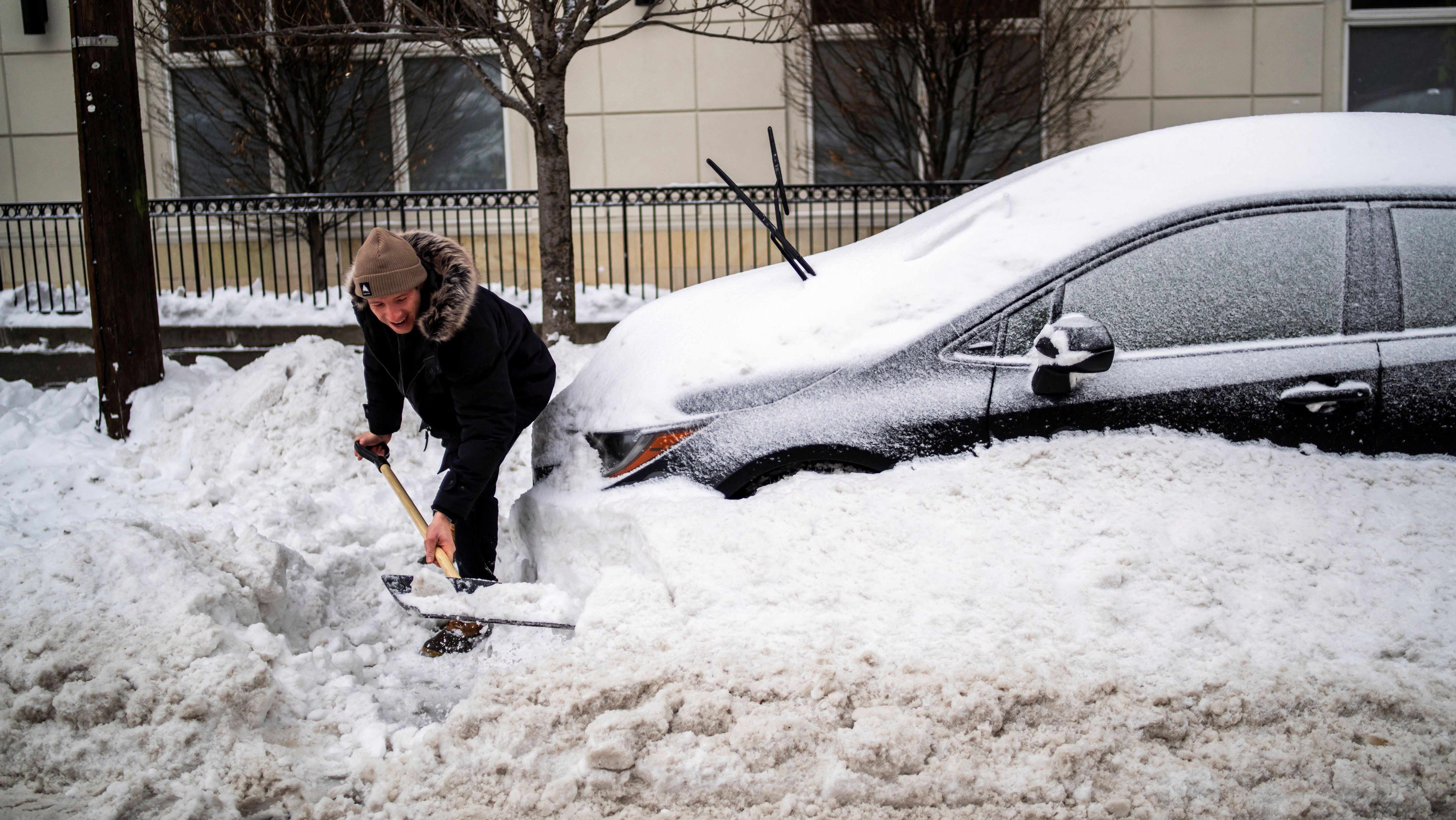 Homem retira neve com pá para liberar o carro em Hoboken, Nova Jersey, enquanto grande tempestade de inverno se espalha pelos Estados Unidos