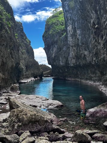 Jake está em pé na água rasa do Abismo de Matapa, na ilha de Niue • Terry Ward
