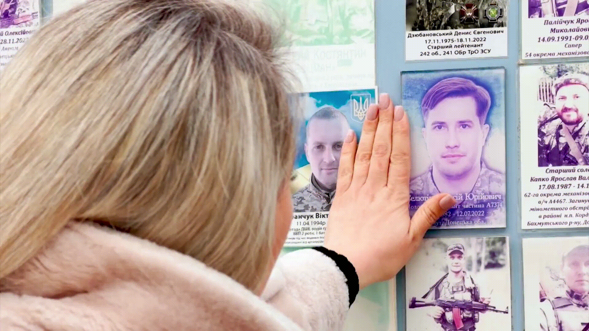 Juliia Seliutina toca o retrato do marido em muro memorial de Kiev. • CNN
