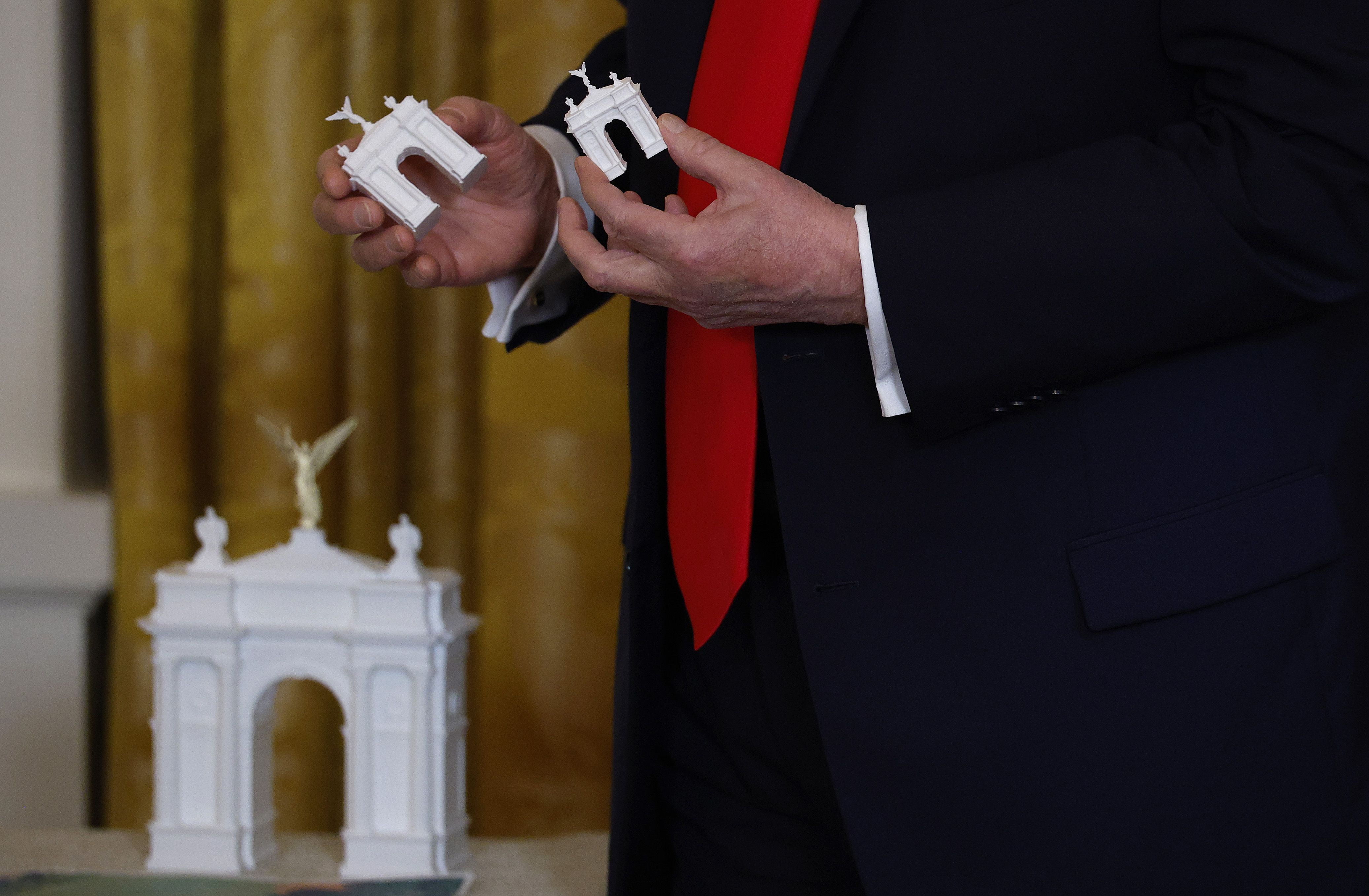 O presidente dos EUA, Donald Trump, segura modelos de arco enquanto faz comentários durante um jantar de arrecadação de fundos no Salão Leste da Casa Branca em 15 de outubro de 2025 em Washington, DC • Kevin Dietsch/Getty Images