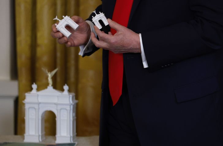 O presidente dos EUA, Donald Trump, segura modelos de arco enquanto faz comentários durante um jantar de arrecadação de fundos no Salão Leste da Casa Branca em 15 de outubro de 2025 em Washington, DC • Kevin Dietsch/Getty Images