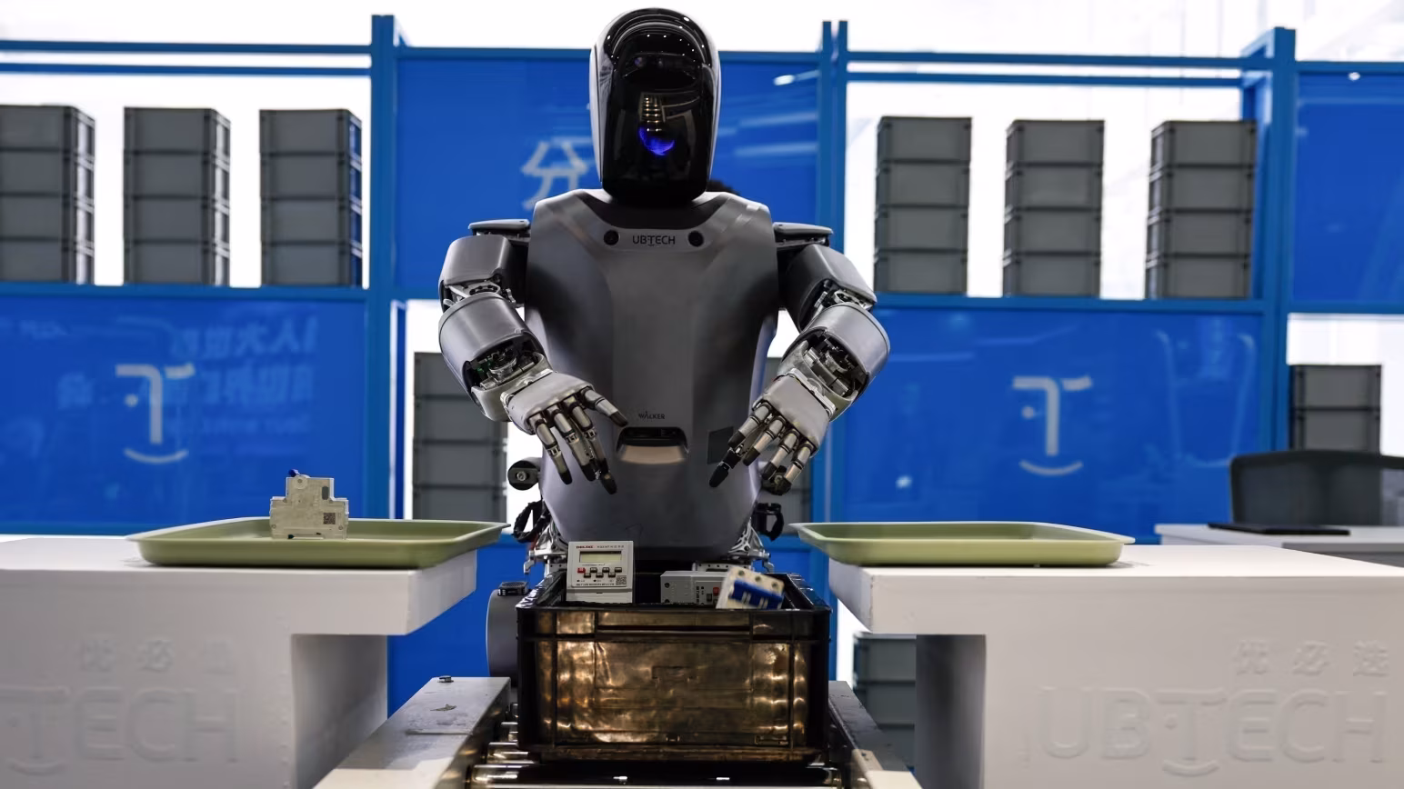 O robô humanoide Walker S, da UBTECH, pegando objetos durante uma demonstração que simula uma linha de montagem de fábrica na Área de Desenvolvimento Econômico e Tecnológico de Pequim, em 16 de maio de 2025.