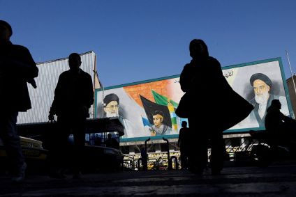 Pessoas caminham perto de um mural com imagens do líder supremo do Irã, o aiatolá Ali Khamenei, e do líder da Revolução Islâmica do Irã de 1979, o aiatolá Ruhollah Khomeini, em uma rua de Teerã, Irã, em 17 de fevereiro.