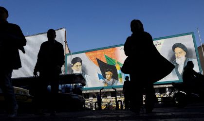 Pessoas caminham perto de um mural com imagens do líder supremo do Irã, o aiatolá Ali Khamenei, e do líder da Revolução Islâmica do Irã de 1979, o aiatolá Ruhollah Khomeini, em uma rua de Teerã, Irã, em 17 de fevereiro.