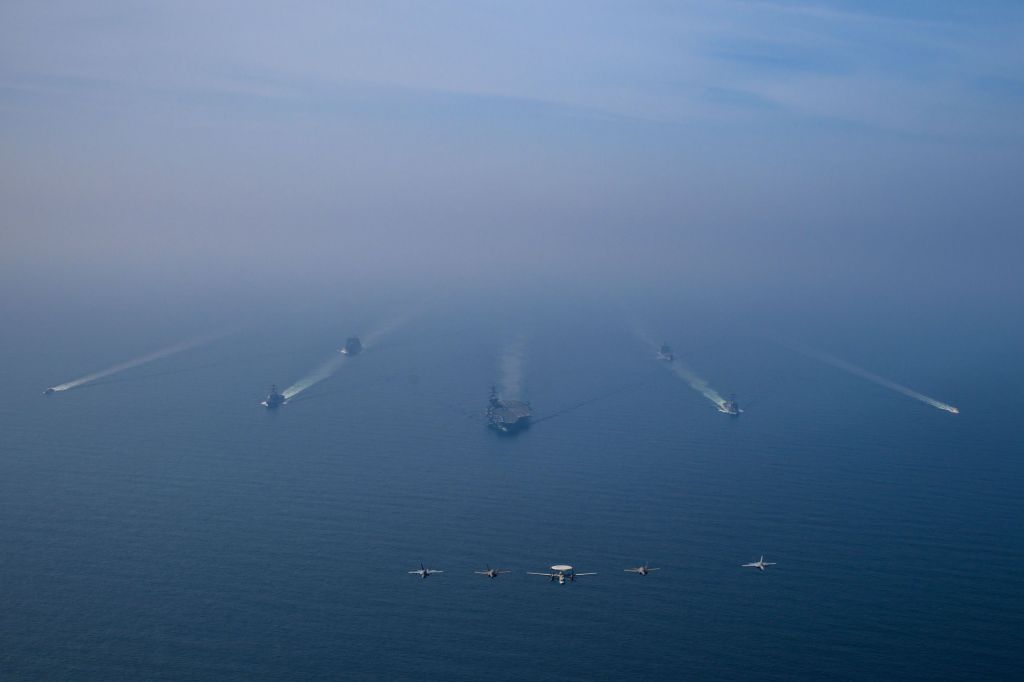 Vista aérea do Grupo de Ataque do Porta-Aviões USS Abraham Lincoln em operação no Mar Arábico, escoltado por dois navios de reabastecimento militar e duas embarcações da Guarda Costeira dos EUA, enquanto caças da Ala Aérea Embarcada Nove realizavam operações de voo sobre o Mar Arábico, em 6 de fevereiro de 2026.